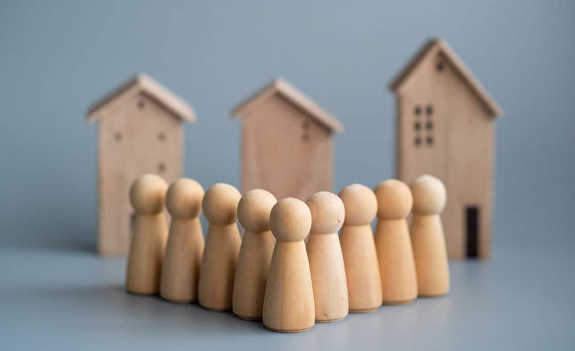Fotografía de peones de madera. Al fondo, casitas de madera.